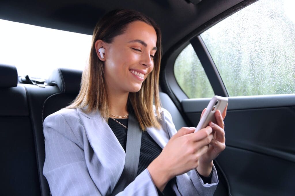 businesswoman with wireless earbuds commuting to work in taxi talking on mobile phone
