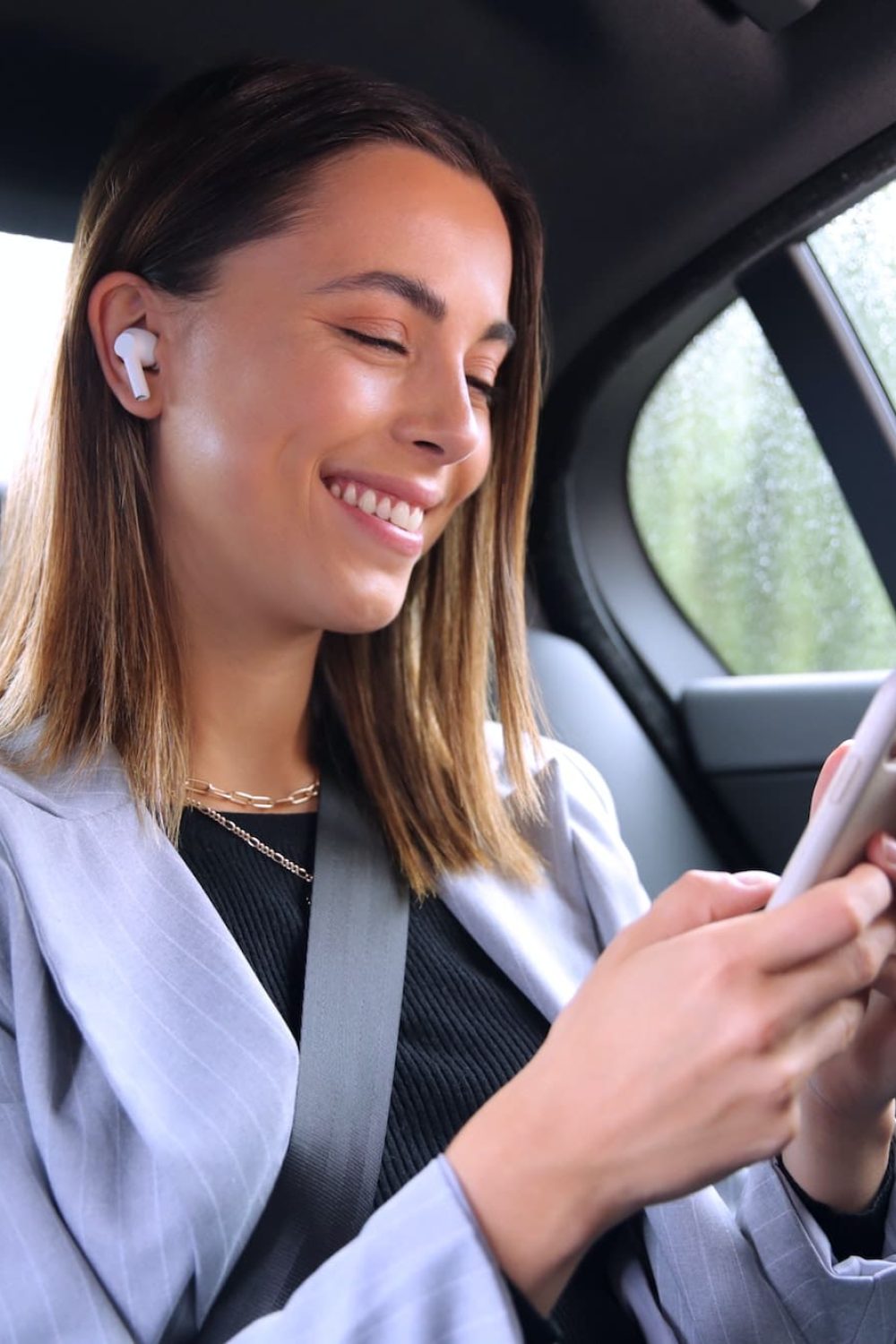 businesswoman with wireless earbuds commuting to work in taxi talking on mobile phone